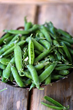 Ahşap bir yüzeyde kabuklu taze bezelyeler..