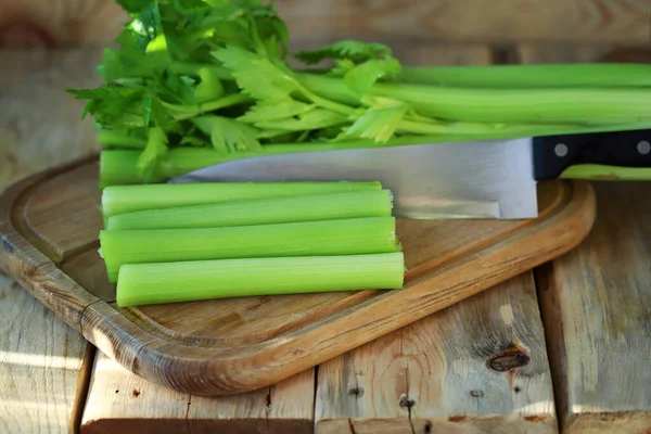 Soft focus. Celery sticks on a wooden board. Fresh celery leaves.