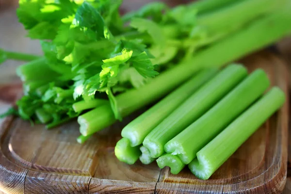 Soft focus. Celery sticks on a wooden board. Fresh celery leaves.