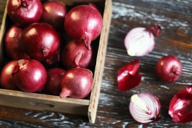 Tahta bir kutuda mavi fiyonk. Kırmızı soğanı kes..