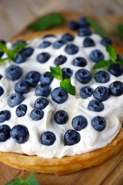 Tart with blueberries and white buttercream. Summer berry dessert.