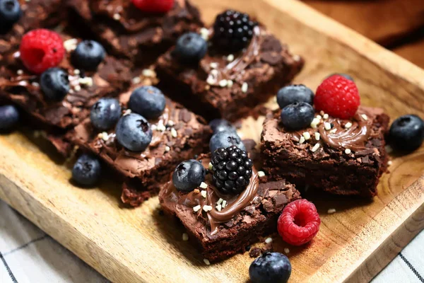 Brownie with berries and chocolate on a wooden board. Homemade vegan brownies.