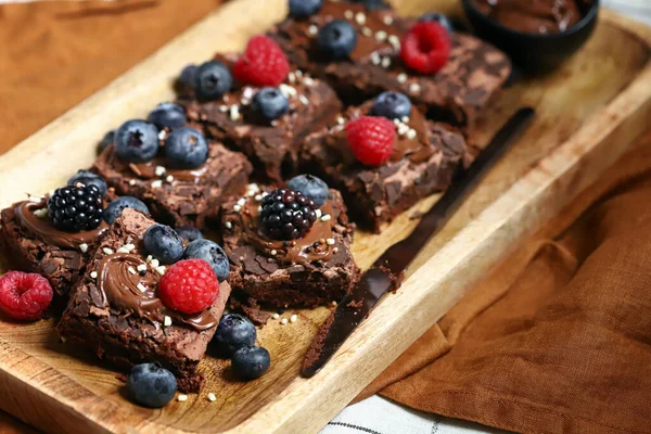 Brownie with berries and chocolate on a wooden board. Homemade vegan brownies.