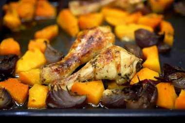 Seçici odaklanma. Makro. Kabak ve mavi soğanlı fırında tavuk budu. Balkabaklı sıcak sonbahar yemeği. Şükran Günü yemeği..