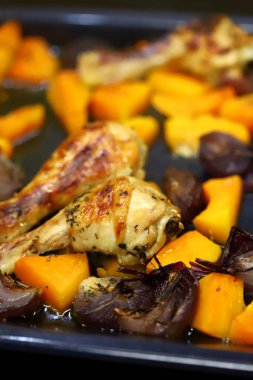 Seçici odaklanma. Makro. Kabak ve mavi soğanlı fırında tavuk budu. Balkabaklı sıcak sonbahar yemeği. Şükran Günü yemeği..