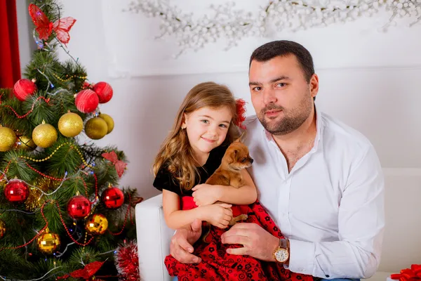 Dad and daughter with dog near the Christmas tree