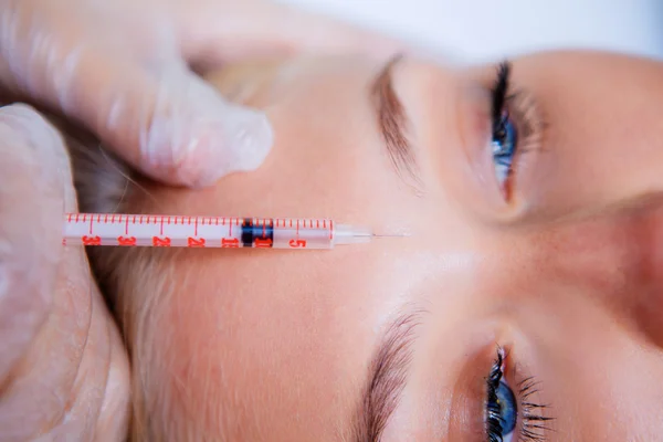Beauty woman giving botox injections on the forehead