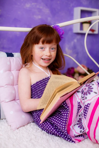 Red-haired girl reading a book on bed
