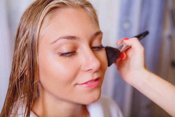 Makeup artist doing makeup for beautiful girl