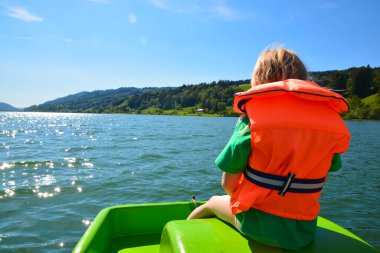 Çocuk can yeleğiyle tekneye biniyor.