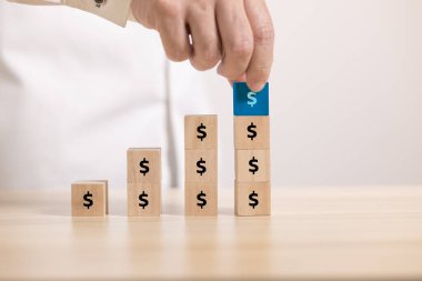 Tahta bloğu dolar simgesiyle yukarı çizgi grafiğine kapatın. Büyüme grafiği ve para tasarrufu kavramı.
