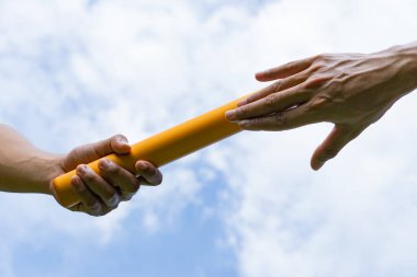 Close up hand set baton from hand to hand on sky background. Business concept for teamwork and team builder.