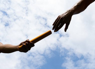 Close up hand set baton from hand to hand on sky background. Business concept for teamwork and team builder.