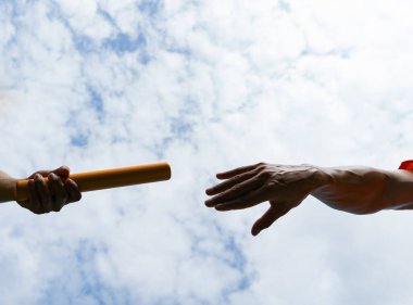 Close up hand set baton from hand to hand on sky background. Business concept for teamwork and team builder.