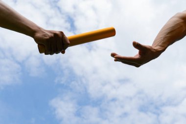 Close up hand set baton from hand to hand on sky background. Business concept for teamwork and team builder.