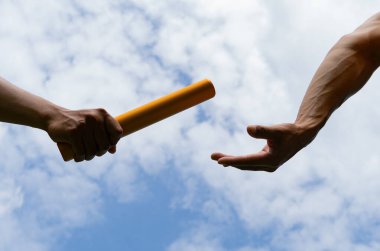 Close up hand set baton from hand to hand on sky background. Business concept for teamwork and team builder.