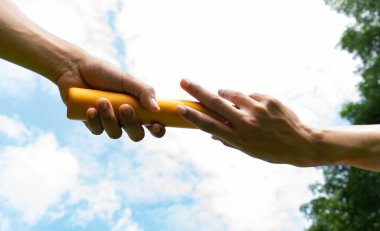 Close up hand set baton from hand to hand on sky background. Business concept for teamwork and team builder.