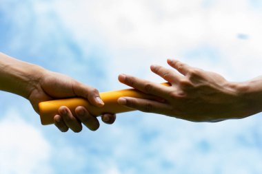 Close up hand set baton from hand to hand on sky background. Business concept for teamwork and team builder.