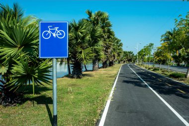 Mavi gökyüzü arka planına sahip bisikletçiler için yol işaretleri ve büyük bir gölet.