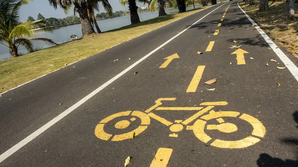 Mavi gökyüzü arka planlı bisikletçiler için yol ve büyük bir gölet.