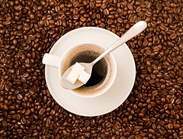 Kopje zwarte koffie over Boon gedekt achtergrond — Stockfoto