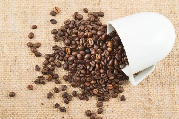 Kopp med kaffebønner over hessisk tøy – stockfoto