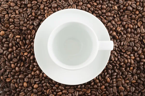 Taza y plato de cerámica sobre granos de café — Foto de Stock