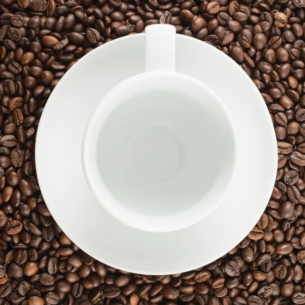 コーヒー豆の背景の上に空のカップ — ストック写真