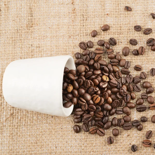 Cup full of coffee beans over hessian cloth — Stock Photo, Image
