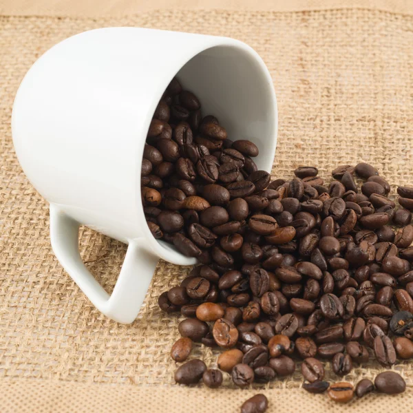 Kopp med kaffebønner over hessisk tøy – stockfoto