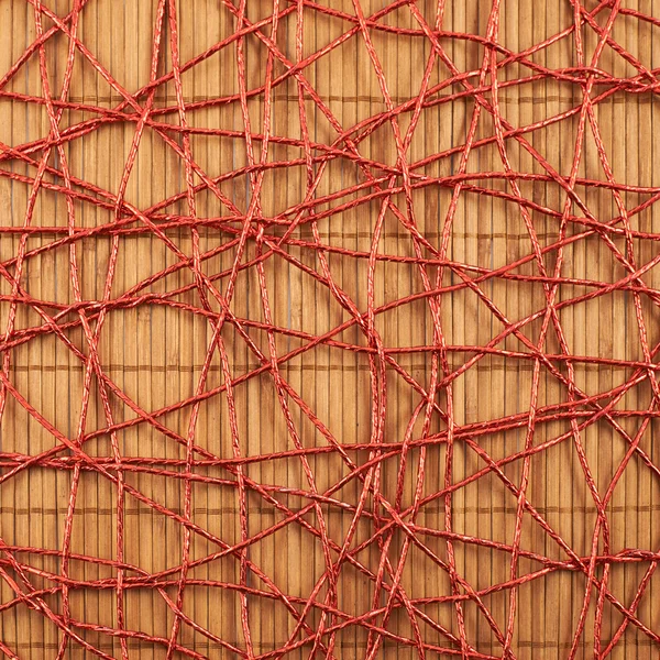 Bamboo mat covered with red thread — Stock Photo, Image