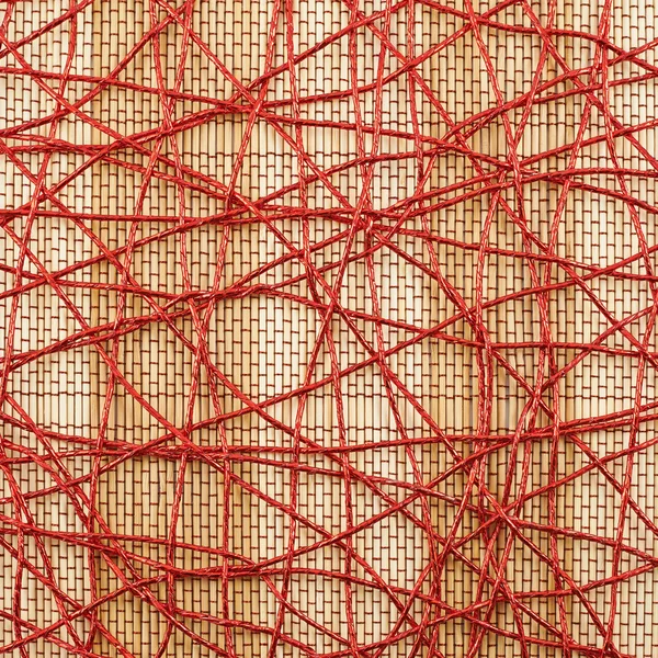 Bamboo mat covered with red thread — Stock Photo, Image