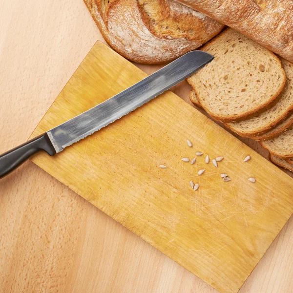 Bread and seeds with cutting board — Stock Photo, Image