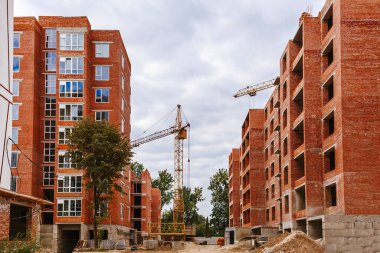 Construction site with many high-rise tall new brick houses and  crane  and building materials on it