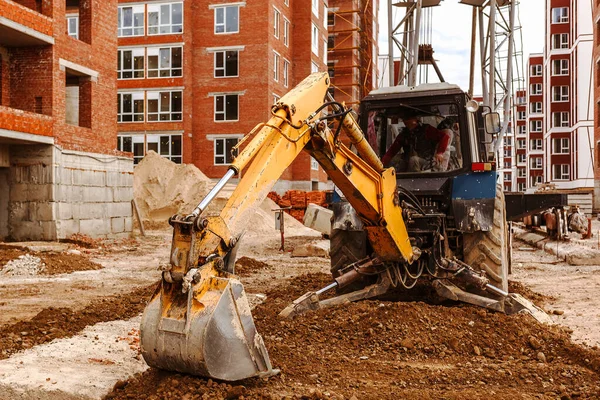 İnşaat makineli inşaat alanı. İnşaat alanında kazıcı ve rane arka planda binalar, seçici odaklı