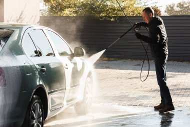 Washing car. Young man washes a car at a self-service car wash.