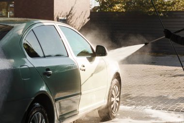 Araba, dışarıdaki otomatik lavabodaki bir hortumun güçlü su basıncının altında yıkanıyor. Araba temizleme kavramı.