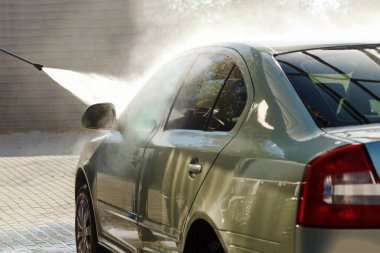 car wash self-service the windshield with vechicle in the city.