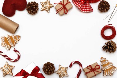 Beyaz bir arka planda Noel hediyeleri çerçevesi. Noel karamelleri, hediye kutuları, zencefilli ekmek ve çam kozalakları