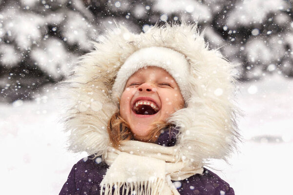 Winter smiling child girl portrait in fur hood. Winter laughing kid face. Winter happy emotions. Positive winter.
