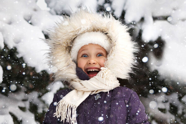 Winter happy smiling portrait close up. Emotional cheerful smile child face in fur hood. Positive winter emotions.