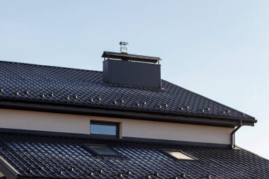 Chimney on house roof top covered with metallic shingles under construction. Real estate development concept. clipart