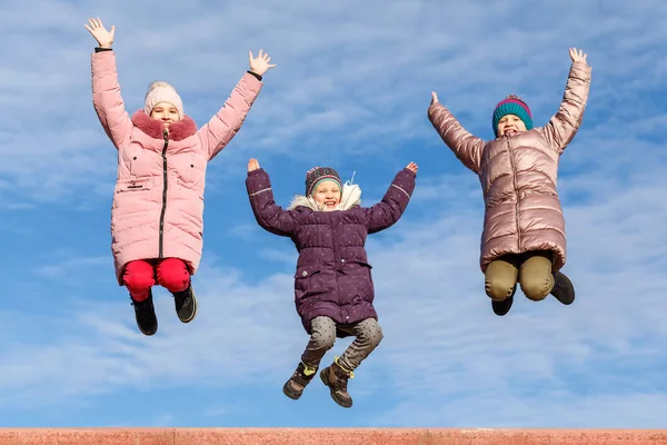 Glückliche Kinder Springen Warmer Kleidung Vor Blauem Himmel Unbeschwerte Glückliche — Stockfoto