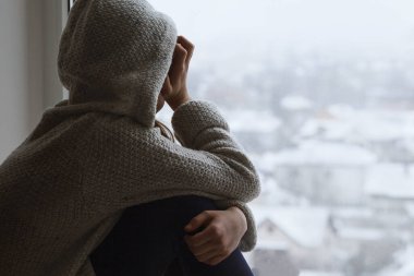 Depresyondaki üzgün genç kız pencereden kameraya bakar. Ergenlikte zor olgunlaşma. Gençlikte olumsuz düşünceler