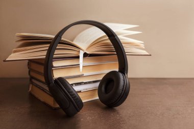 Ses kitabı konsepti. Kulaklıklar kahverengi arka plandaki kitaplarda. Uzayı kopyala Dünya Kitap Günü