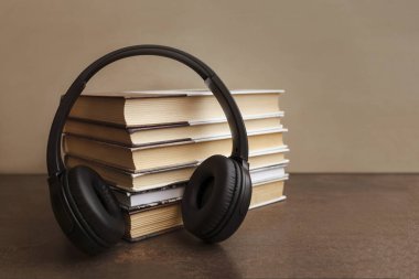 Ses kitabı konsepti. Kulaklıklar kahverengi arka plandaki kitaplarda. Uzayı kopyala Dünya Kitap Günü