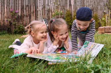 Çocuklar yalancı çim oynar. Üç çocuk bahçede masa oyunu oynuyor.. 