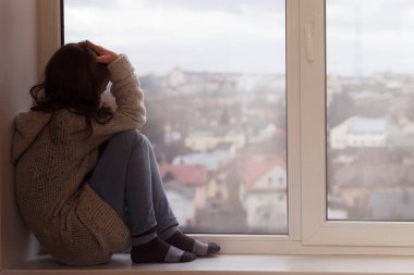 Stresli üzgün ergen yalnız başına oturup pencereden dışarı bakıyor. Depresyondaki Üzgün Genç 'in sorunları var. Olumsuz düşünceler. Ergenlikte depresyon.