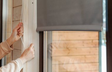 Kumaş pencereyi kör eder. Kız pencereyi panjurlarla kapatır