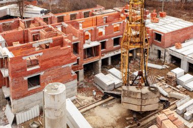 İnşaat alanı, tuğla evler, inşaat malzemeleri, tuğla paletler, vinçler, beton döşemeler. İnşaat Çok Katlı Evler